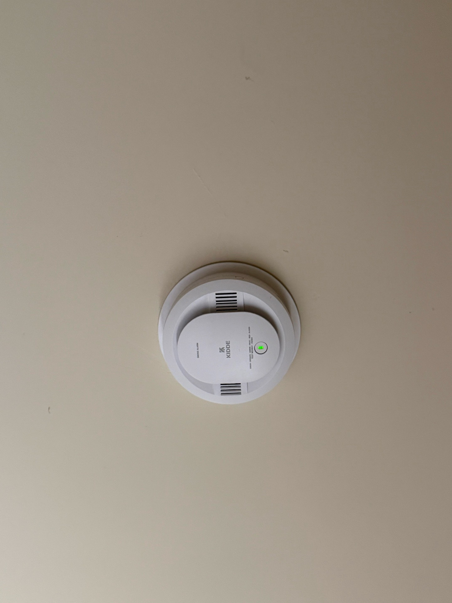 Newly installed smoke alarm on a plain ceiling