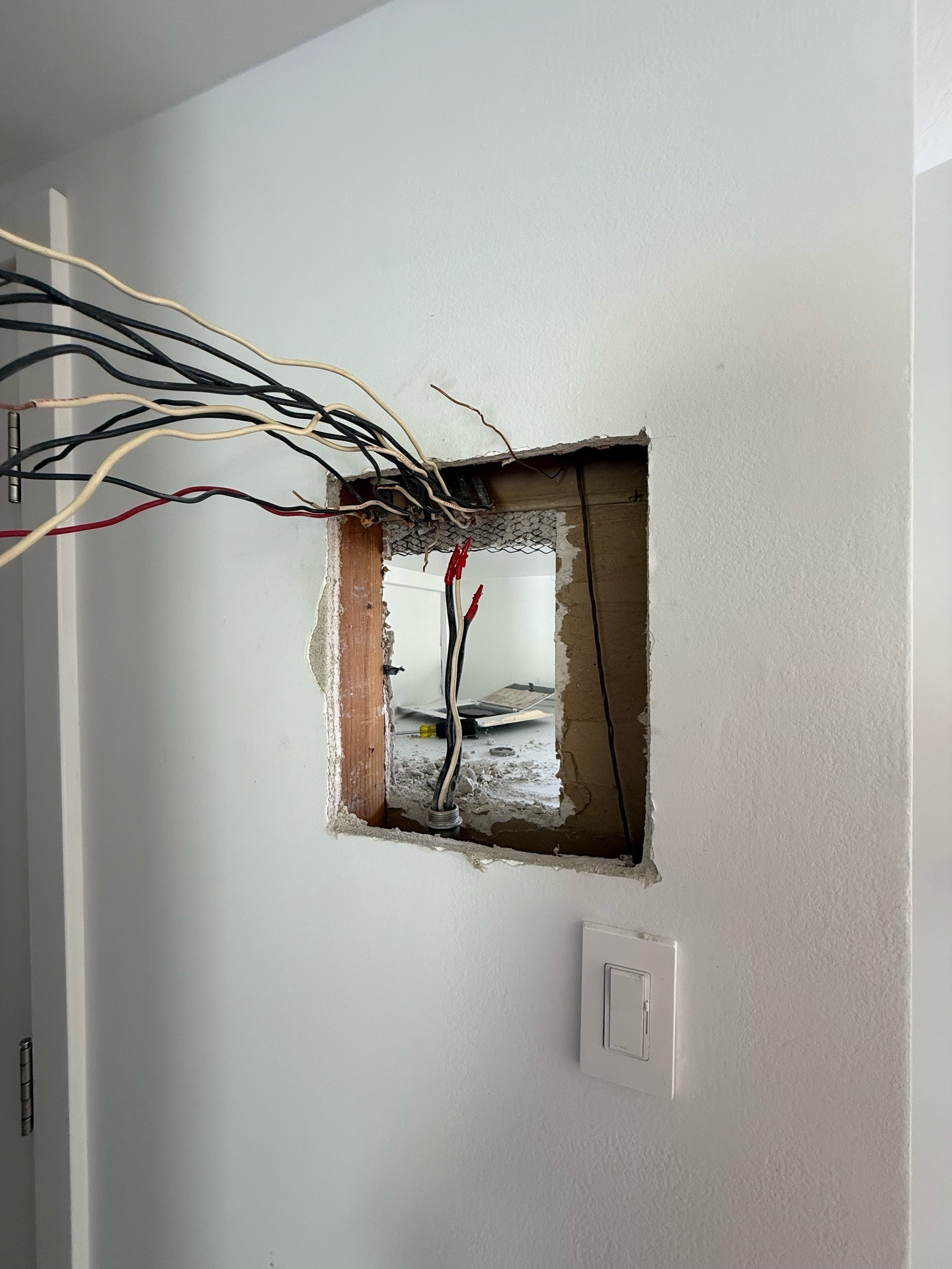 Wall opening and conductors during subpanel relocation, before the finished subpanel was installed